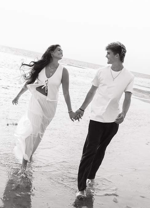 Couple holding hands apart from eachother and looking at eachother