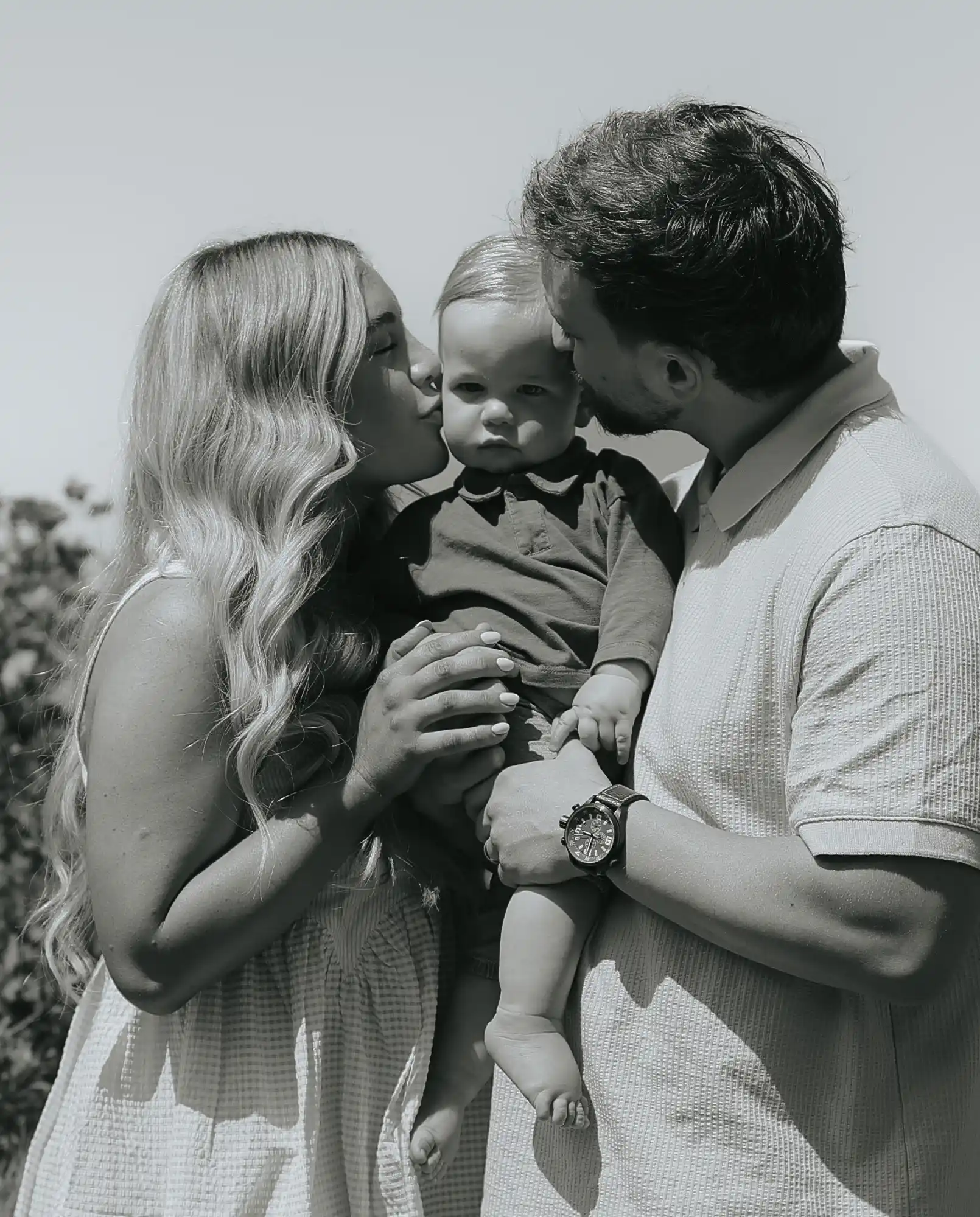 Mom and dad kissing baby's cheek