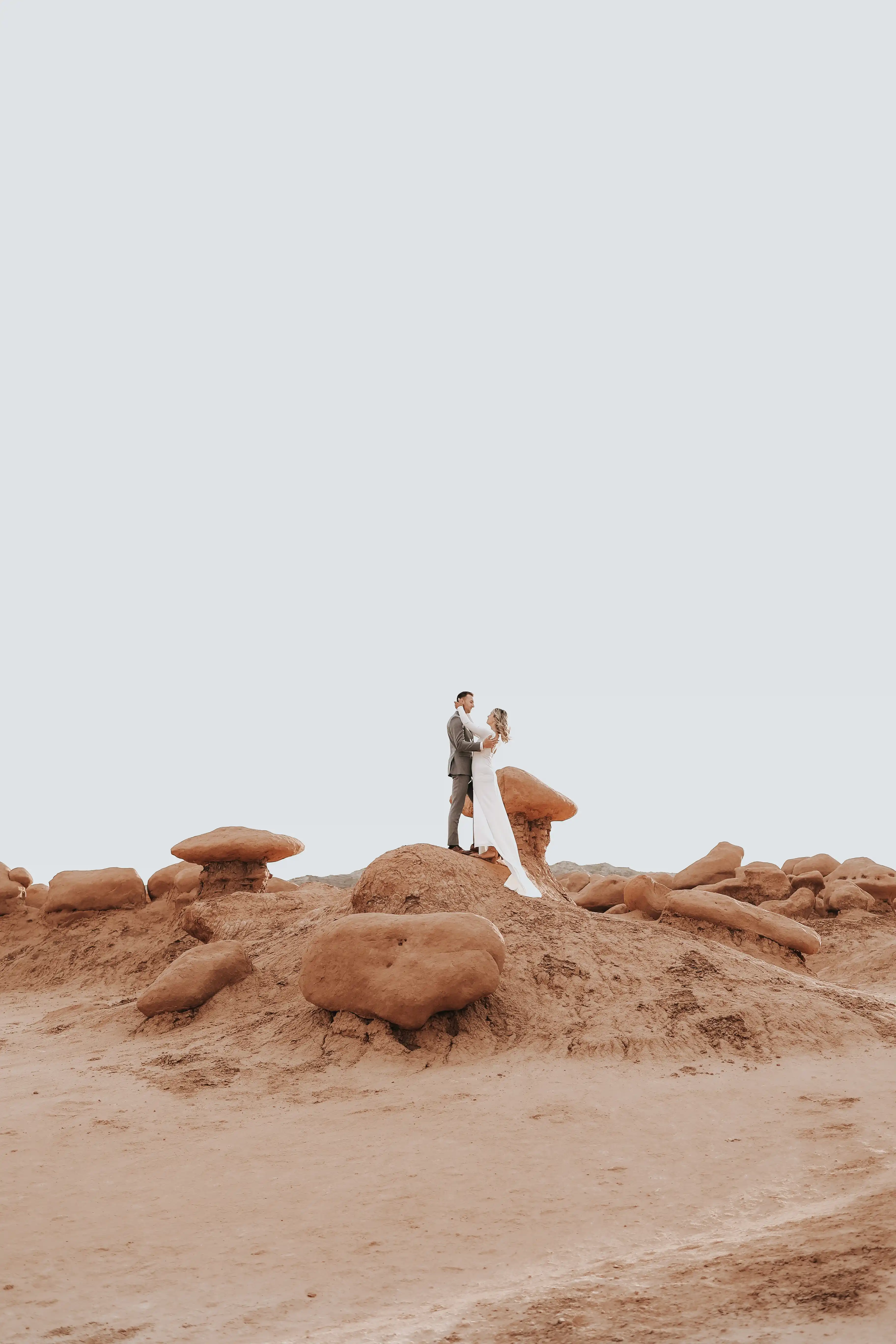 Bride and groom facing each other on a rock
