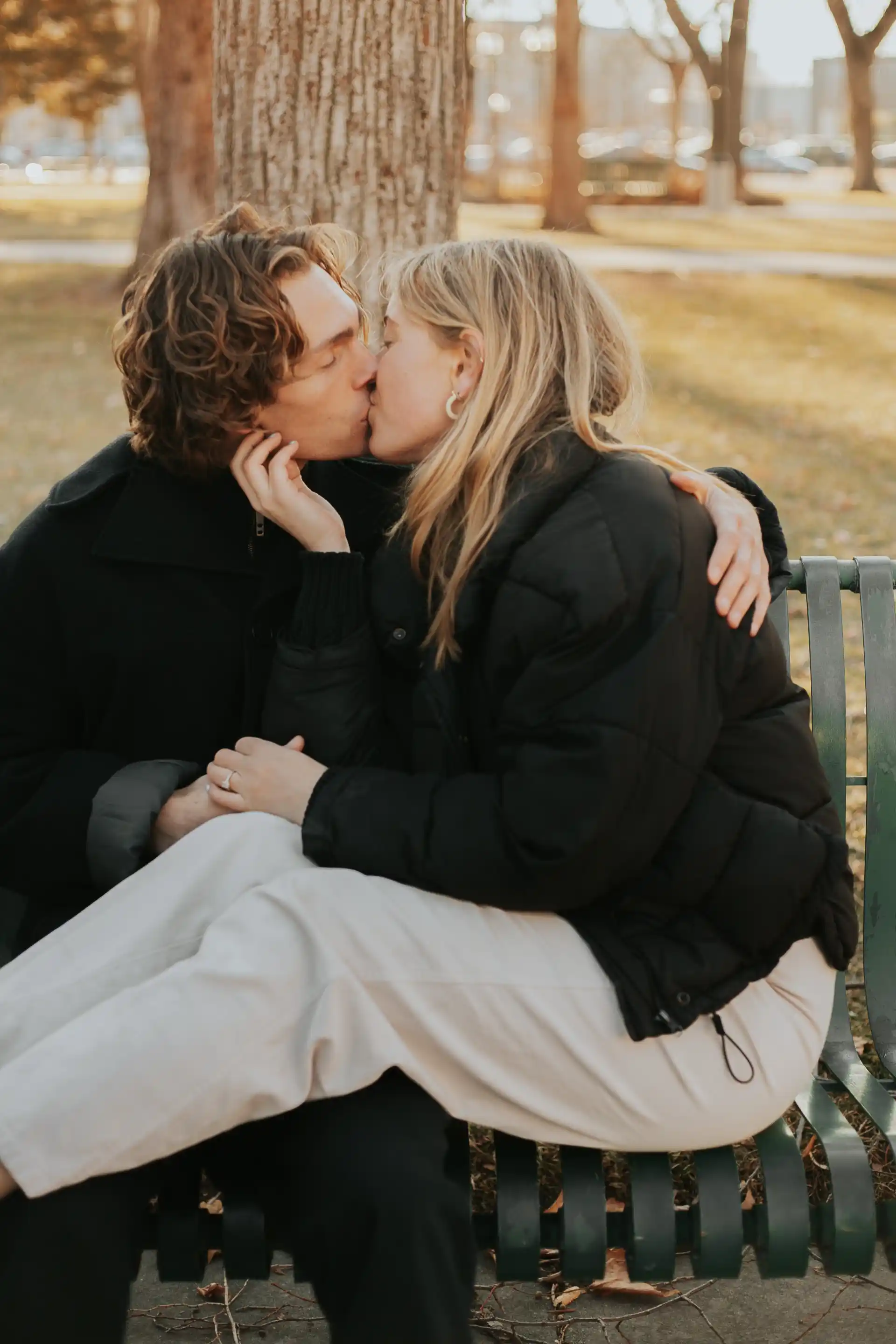 Boy and girl kissing on a park bench